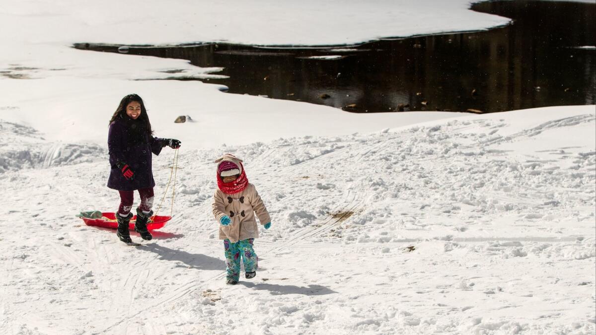 Juanita Garcia of Apple Valley and her daughter Alexis, 4, walk up a snowy slope to go sledding in Big Bear after several inches of snow fell in the San Bernardino National Forest on Tuesday.