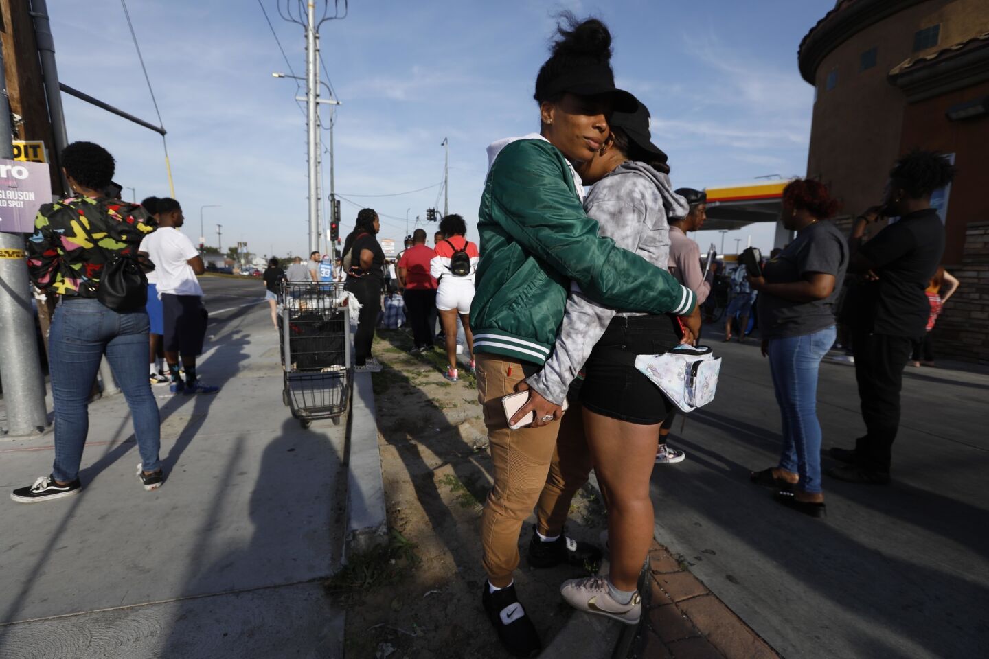Utopia Kates, 27, in green jacket, comforts a friend over the shooting death of rapper Nipsey Hussle outside his clothing store in South Los Angeles.