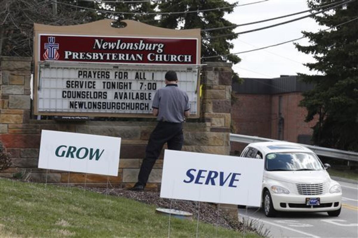Mike Kane, a parishioner at the Newlonsburg Presbyterian Church in Murrysville, Pa., works on a sign outside his church before a prayer service for victims of the high school stabbing.