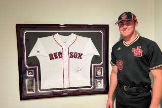 JSerra first baseman Dominic Smaldino poses next to uniform of his grandfather, Jerry Stephenson.