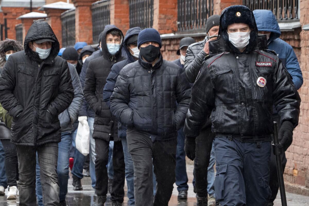 ARCHIVO - unos agentes de la policía acompañan a un grupo de migrantes, en San Petersburgo, Rusia. 