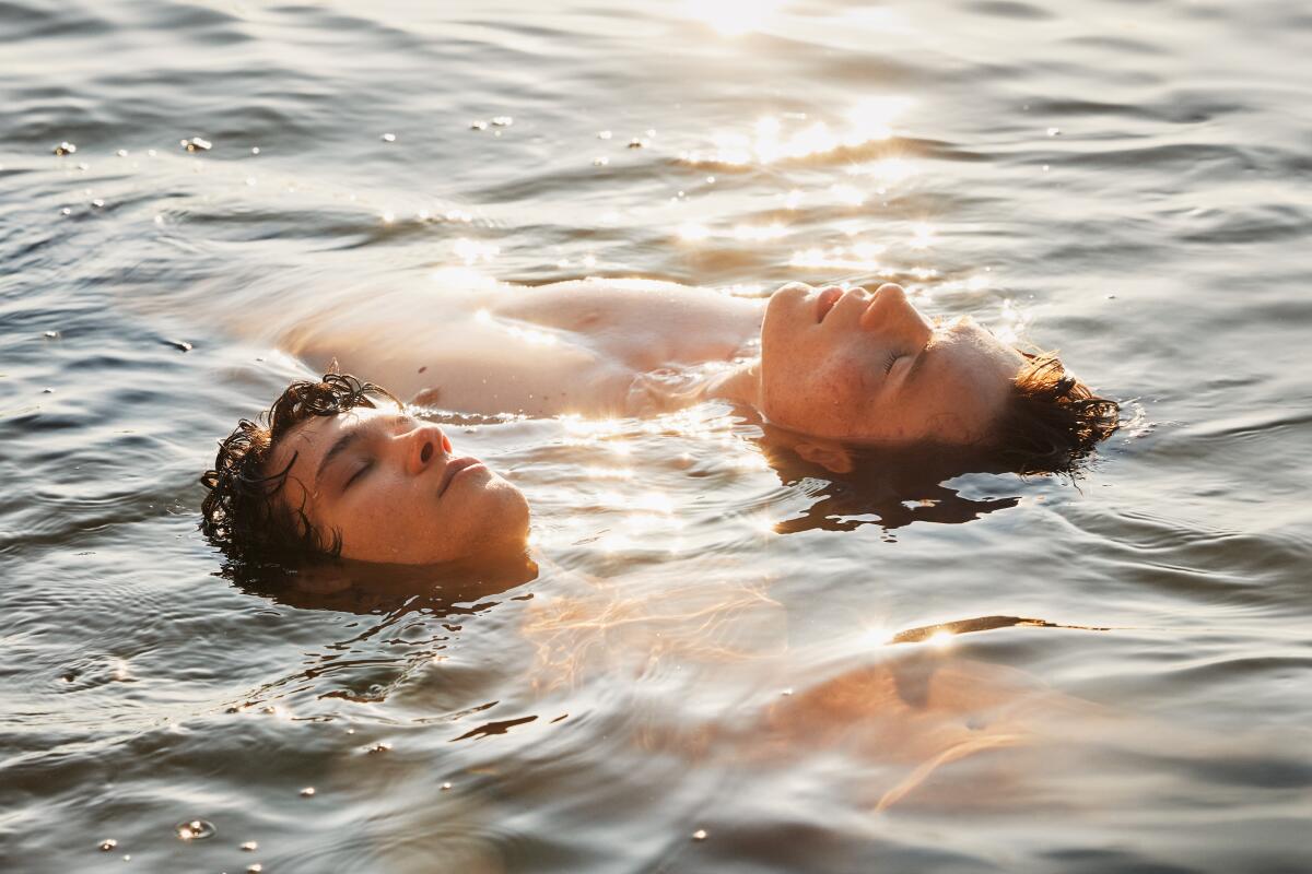两个男孩漂浮在水中，头和部分胸部可见。