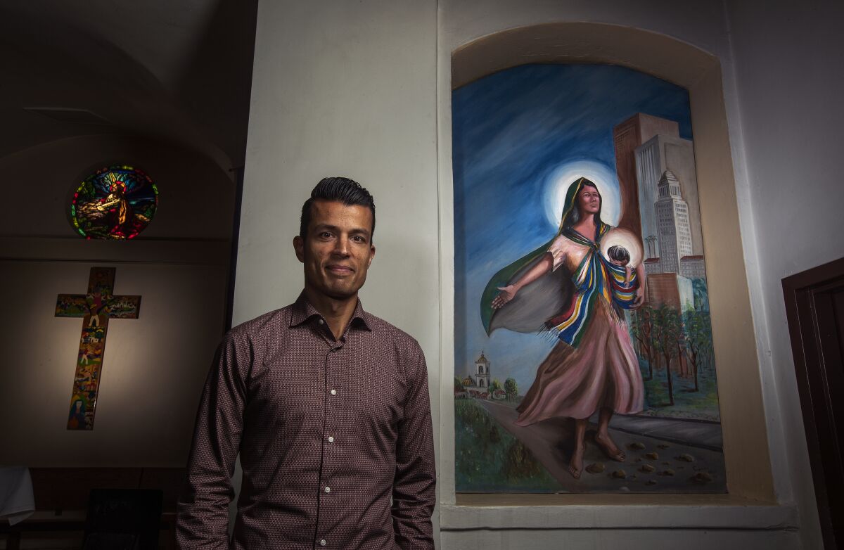 A man standing near a cross and mural of Mary and Jesus in a church