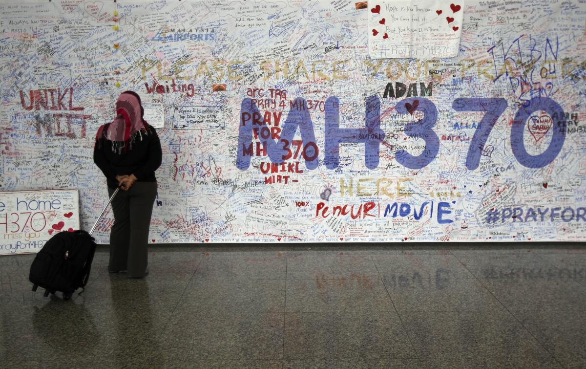 A woman reads messages for passengers aboard a missing Malaysia Airlines plane at Kuala Lumpur International Airport in Sepang, Malaysia, on Tuesday.