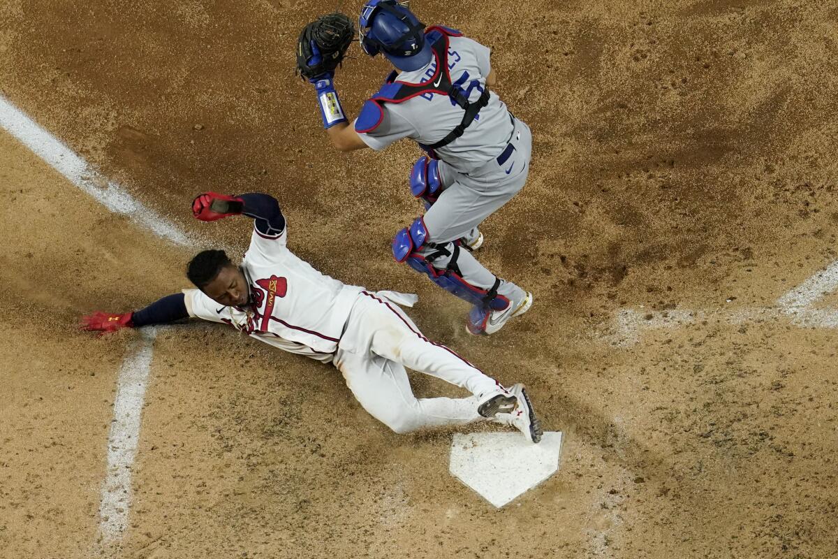 Atlanta's Ozzie Albies scores past Dodgers catcher Austin Barnes on a double by Dansby Swanson during the sixth inning.