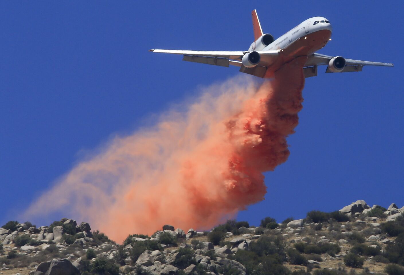 A DC-10 tanker drops retardant ahead of the fire line on the mountains above Snow Creek Village near Cabazon as the 16,000-acre Silver fire in Riverside County continues to burn.
