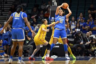 UCLA center Lauren Betts holds the ball up and looks to pass during a Pac-12 tournament game against USC