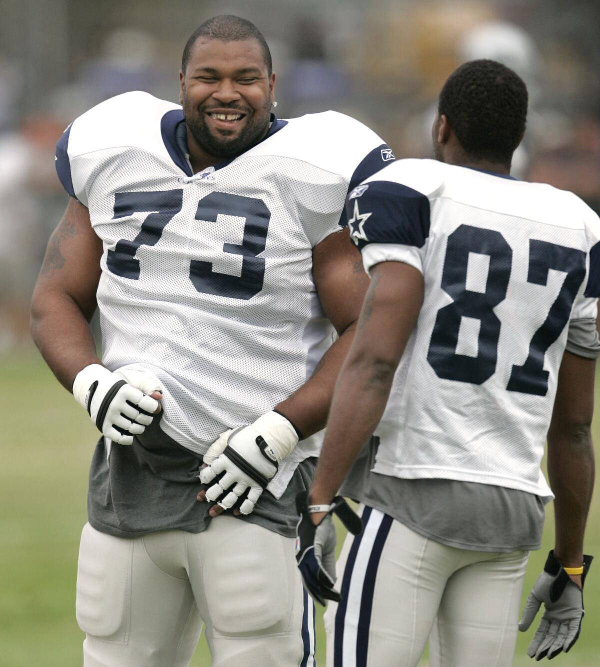 Dallas Cowboys guard Larry Allen shares a laugh with teammate Zuriel Smith during training camp in Oxnard.