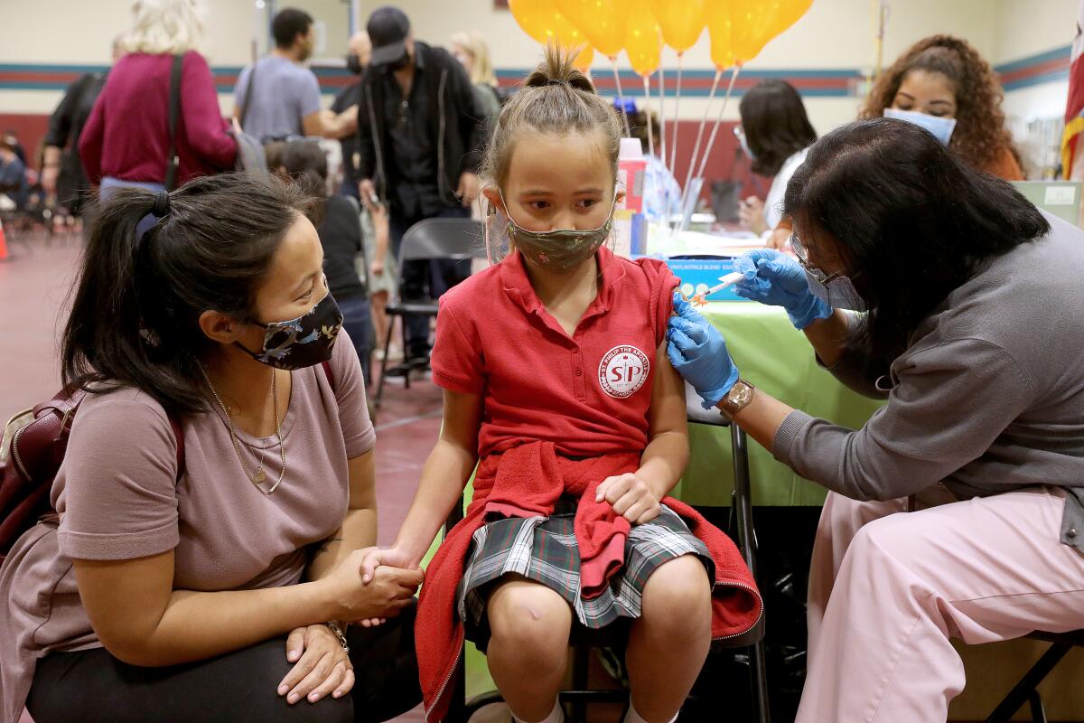 Nicole Fahey, of Altadena, provides moral support for daughter Adeline, 6, as she receives a child’s dose.