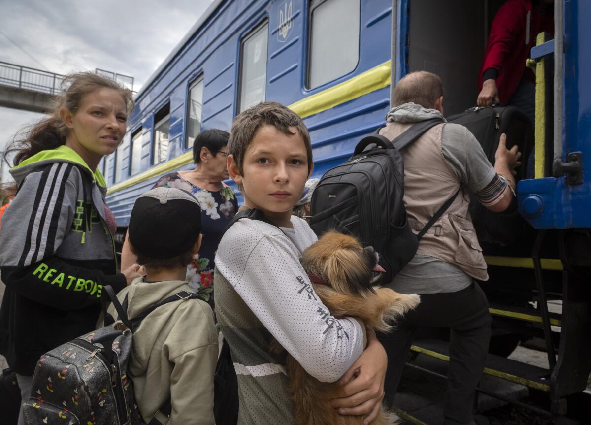 A boy holds his dog and people board a train