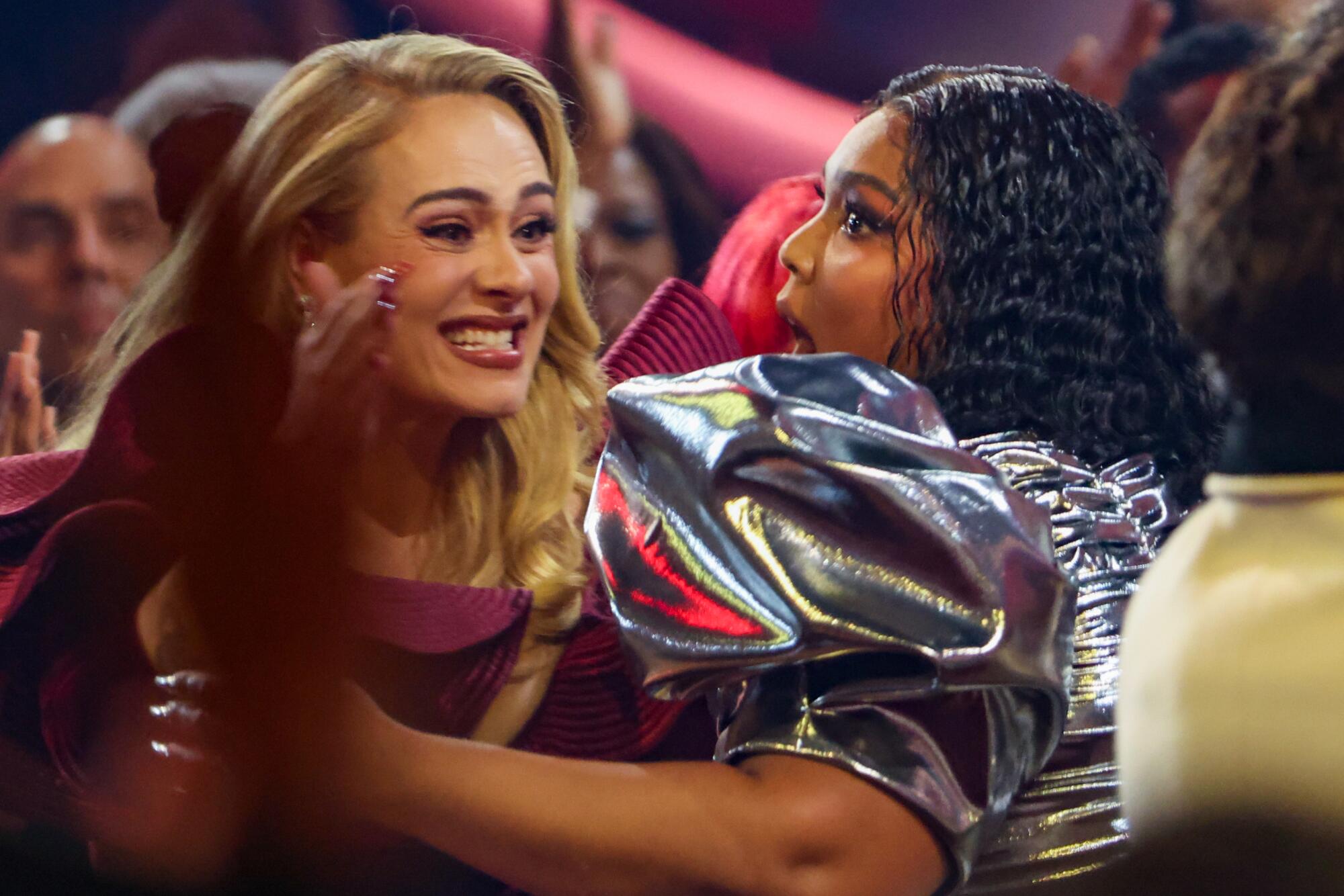 Lizzo abraza a Adele cuando se levanta para aceptar el premio a la grabación del año en la 65ª entrega de los premios Grammy.