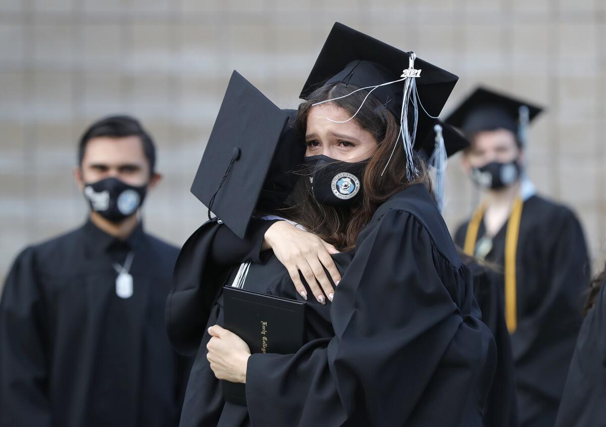 Graduates share a tearful embrace at the Early College High School graduation at Estancia High's Jim Scott Stadium Thursday.