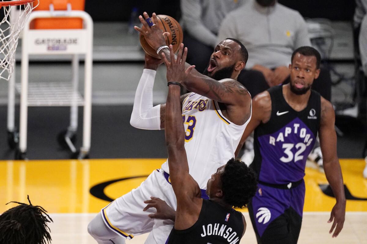 Los Angeles Lakers forward LeBron James, upper left, shoots as Toronto Raptors forward Stanley Johnson, lower left, and guard Rodney Hood defend during the first half of an NBA basketball game Sunday, May 2, 2021, in Los Angeles. (AP Photo/Mark J. Terrill)