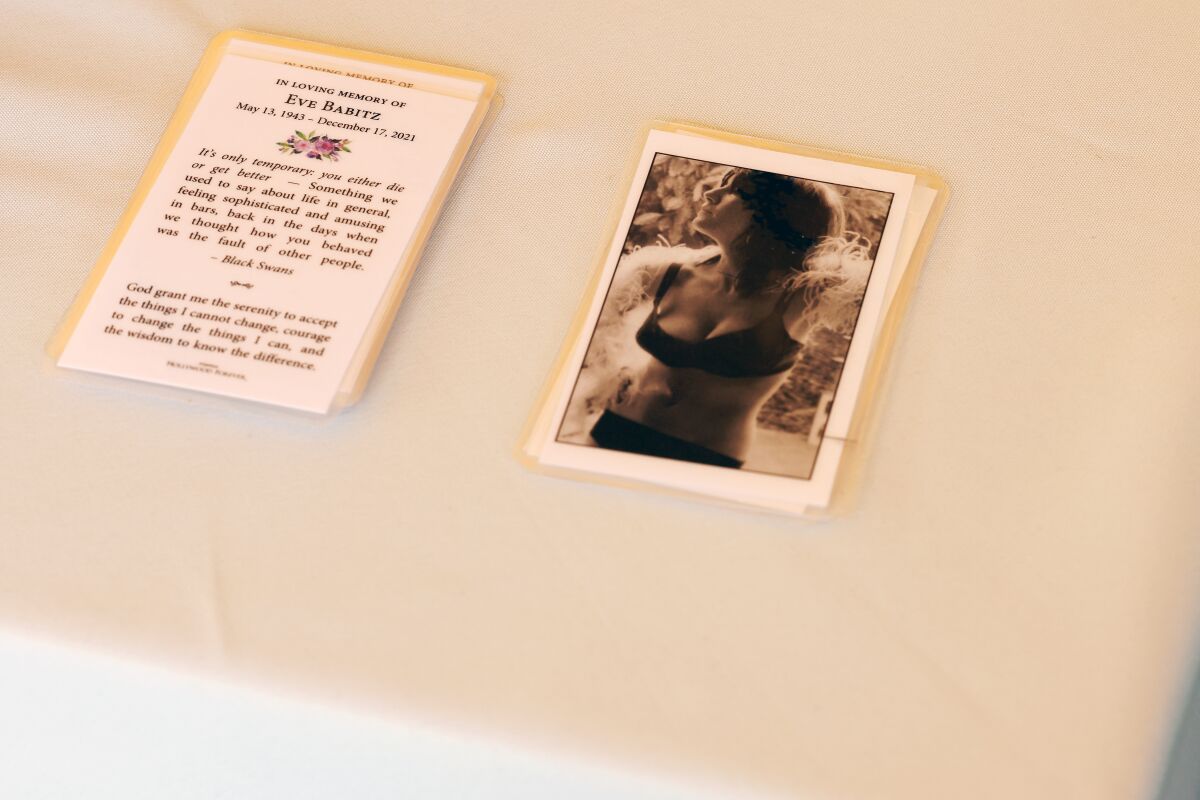 Memorial cards with a prayer and an image of Eve Babitz in a bra and underwear sit on a table.