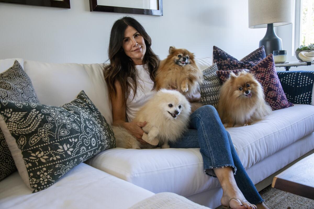 Aimee Tully of Newport Beach poses at home with her three Pomeranians, Ace, left, Myshka and Noel. 