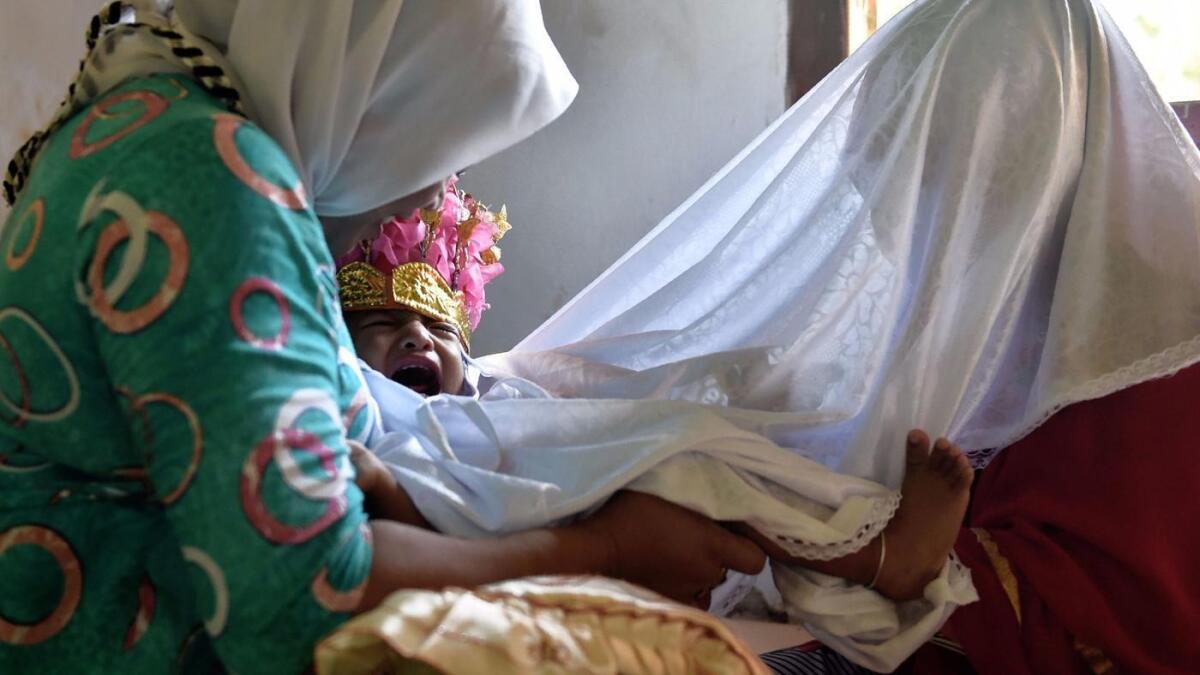 Una niña llora mientras un sanador tradicional le practica una circuncisión femenina, en Indonesia.