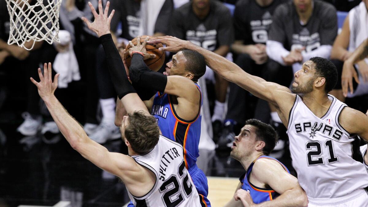 Oklahoma City's Russell Westbrook, center, goes up for a shot between San Antonio Spurs teammates Tiago Splitter, left, and Tim Duncan, right, during the Spurs' 122-105 win in Game 1 of the Western Conference finals Monday.