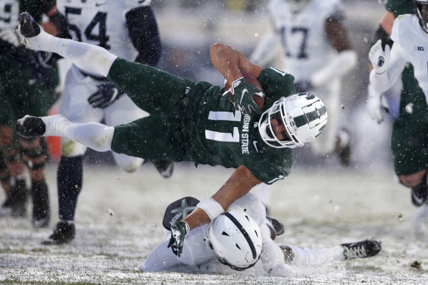 Michigan State's Connor Heyward (11) is upended by Penn State's Kalen King, bottom, during the second quarter of an NCAA college football game, Saturday, Nov. 27, 2021, in East Lansing, Mich. (AP Photo/Al Goldis)