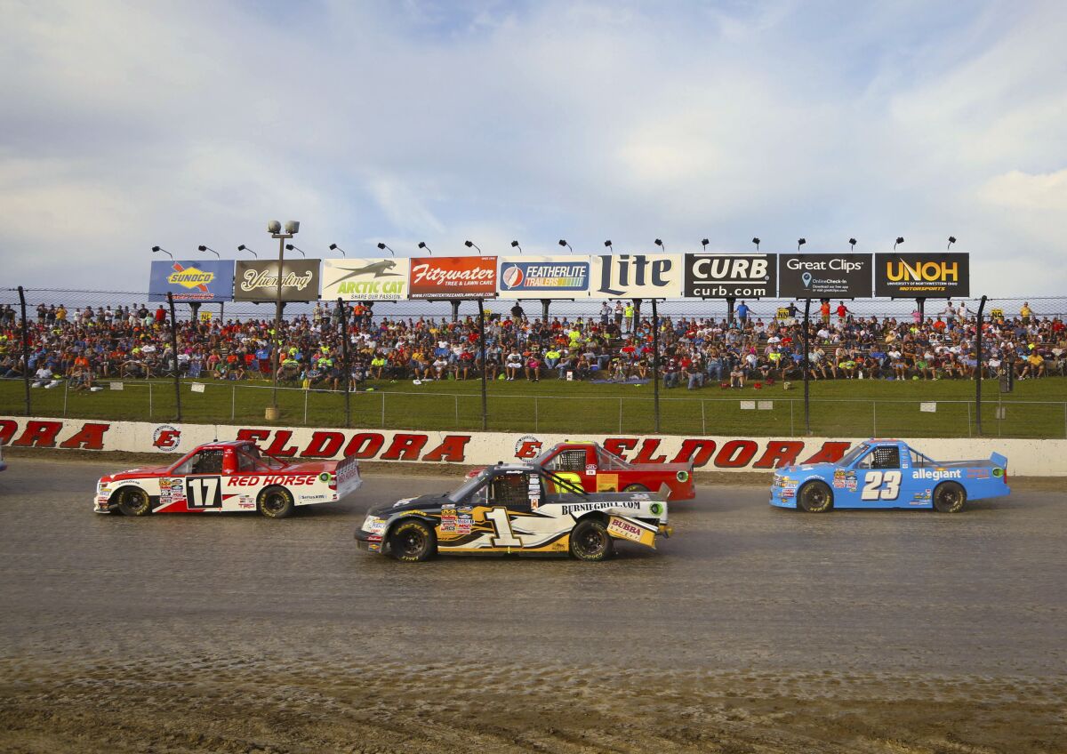 FILE - Trucks race past grandstands on the back stretch during the third qualifying race for the NASCAR Truck Series' Mud Summer Classic auto race at Eldora Speedway in Rossburg, Ohio, Wednesday, July 22, 2015. Tony Stewart will pay $1,002,022 on Thursday night, June 9, 2022, to the winner of the Eldora Million dirt late model race at Eldora Speedway in Rossburg, Ohio. The Thursday night payout will be the second-largest purse in motorsports only to the Indianapolis 500.(Jim Witmer/Dayton Daily News via AP, File)