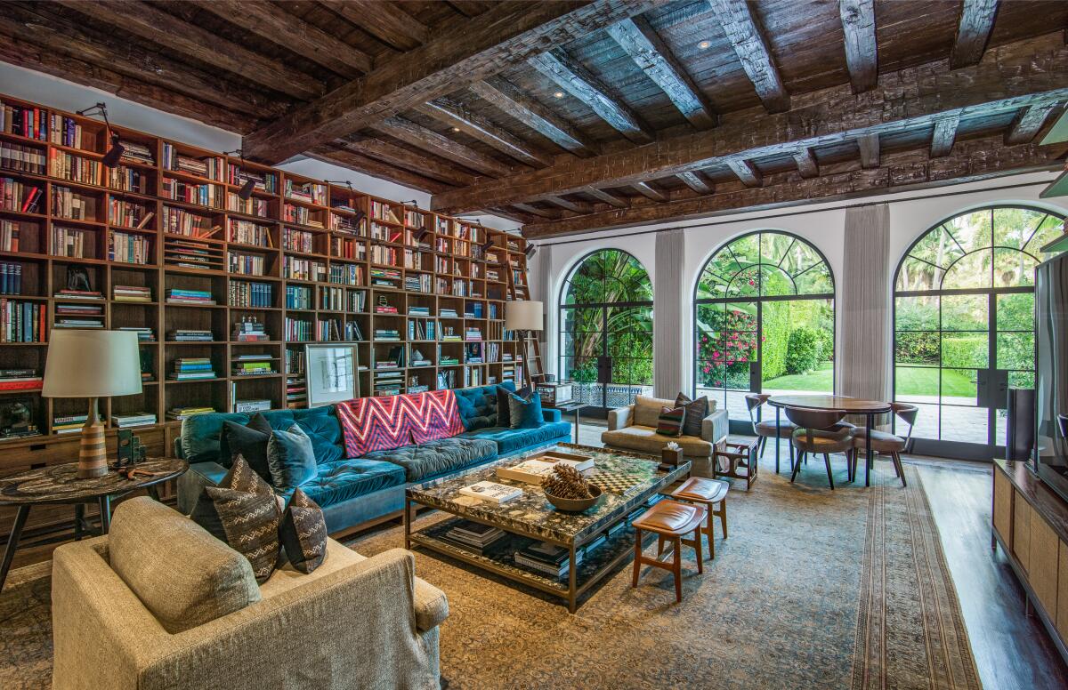 Floor-to-ceiling bookshelves line one wall of a large, rectangular room; large arched windows line another.