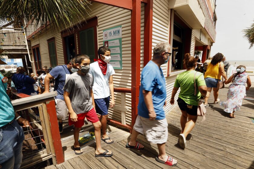 GALVESTON, TEXAS-JULY 3, 2020-Customers comply with the mandatory face mask order at The Spot, a popular restaurant and bar on the boardwalk in Galveston Beach. The beaches are closed on Galveston island for the 4th of July weekend, and there is a mandatory mask order in place, but that hasn't stopped people from visiting this beach city. (Carolyn Cole/Los Angeles Times)