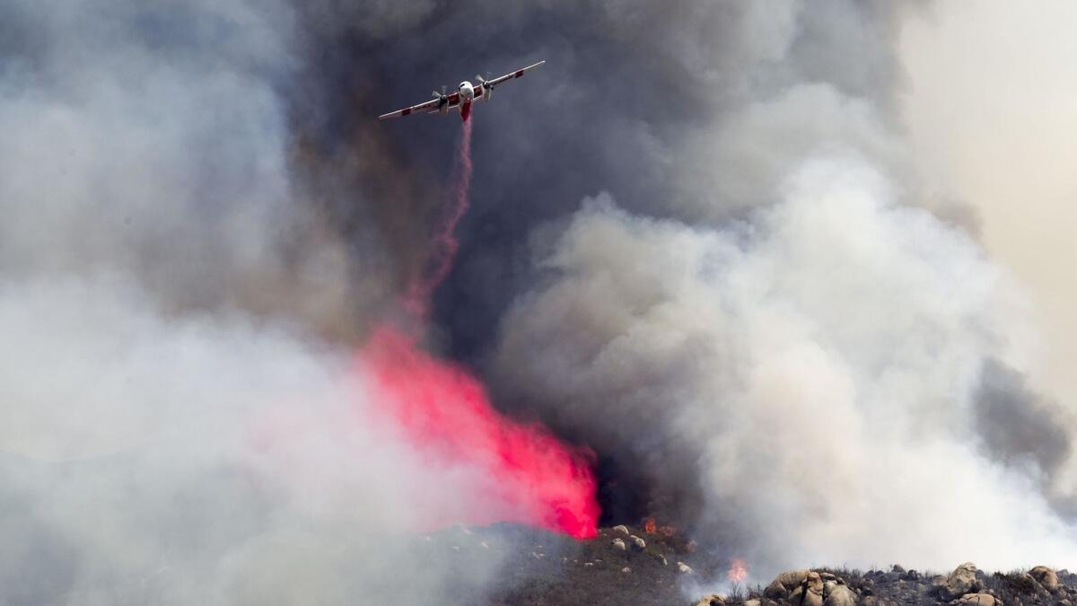 A helicopter attacks flames east of the San Diego Zoo Safari Park.