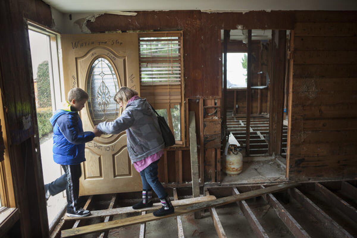 Lori Rebimbas helps her son, Nick, 9, onto a board placed across the remains of the floor of their Point Pleasant, N.J., home, which was badly damaged by Superstorm Sandy.