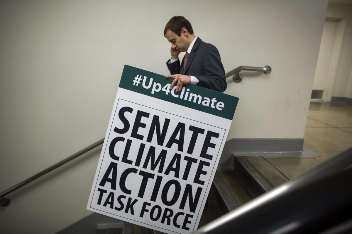 Seth Larson, communications director for Democratic Senator from Rhode Island Sheldon Whitehouse, carries away a sign used on the Senate floor when 28 Democratic and Independent Senators spoke through the night on confronting climate change on March 11.