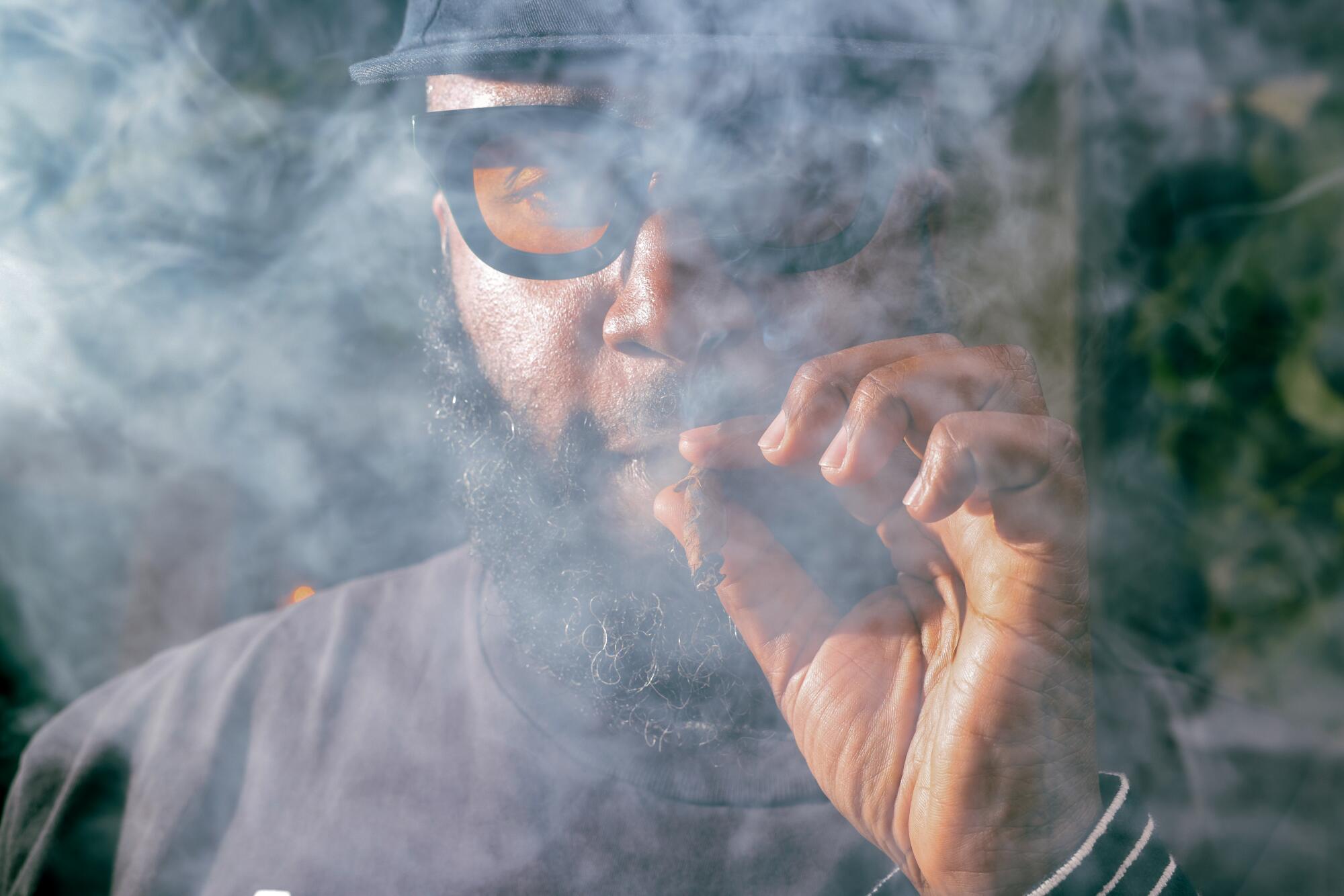 A man smoking a blunt with smoke around his head.