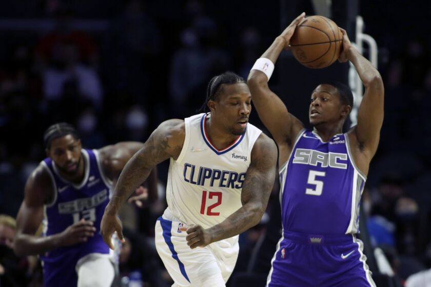 Sacramento Kings guard De'Aaron Fox (5) pulls back the ball as Los Angeles Clippers guard Eric Bledsoe (12) takes a swipe at the ball during the first half of a preseason NBA basketball game Wednesday, Oct. 6, 2021, in Los Angeles. (AP Photo/Alex Gallardo)