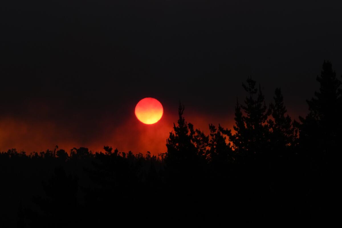 The sun sets in a smoke-filled sky.