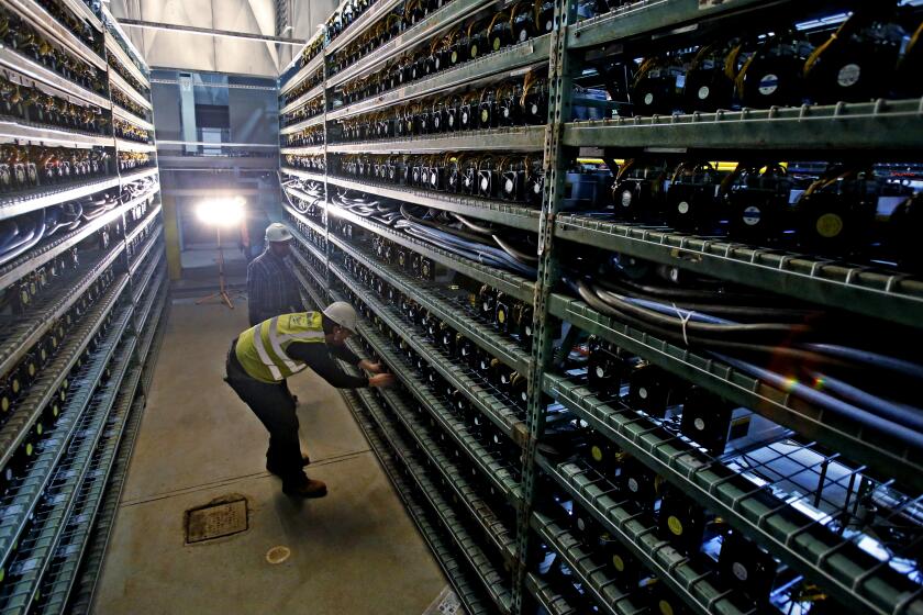 Workers look over racks of Bitcoin data miners during construction of a Bitcoin data center in Virginia Beach, Va., Friday, Feb. 9, 2018. (AP Photo/Steve Helber)