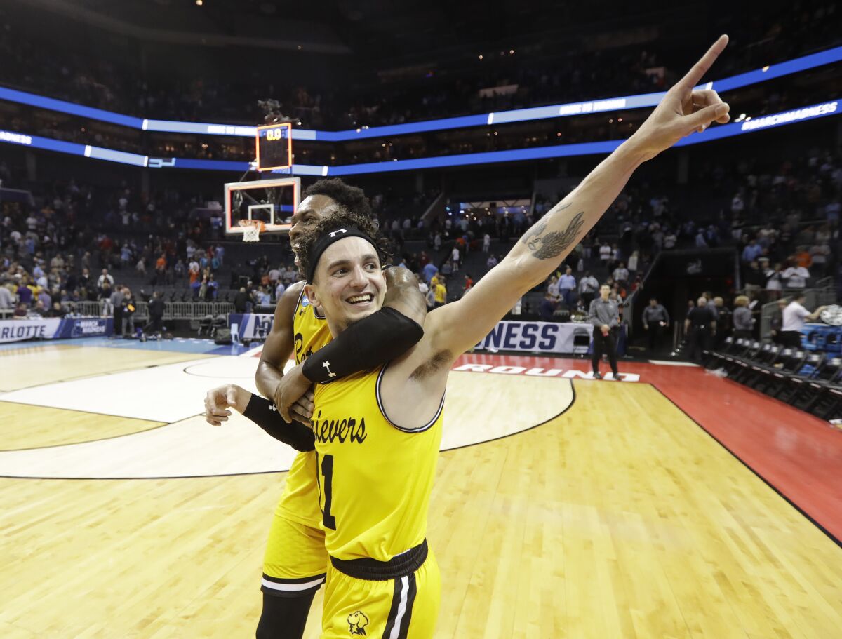 UMBC's K.J. Maura (11) and Jourdan Grant celebrate the team's 74-54 win over Virginia in a first-round game