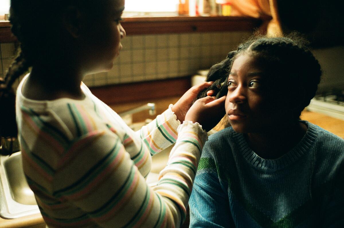 A girl braids her younger sister's hair.