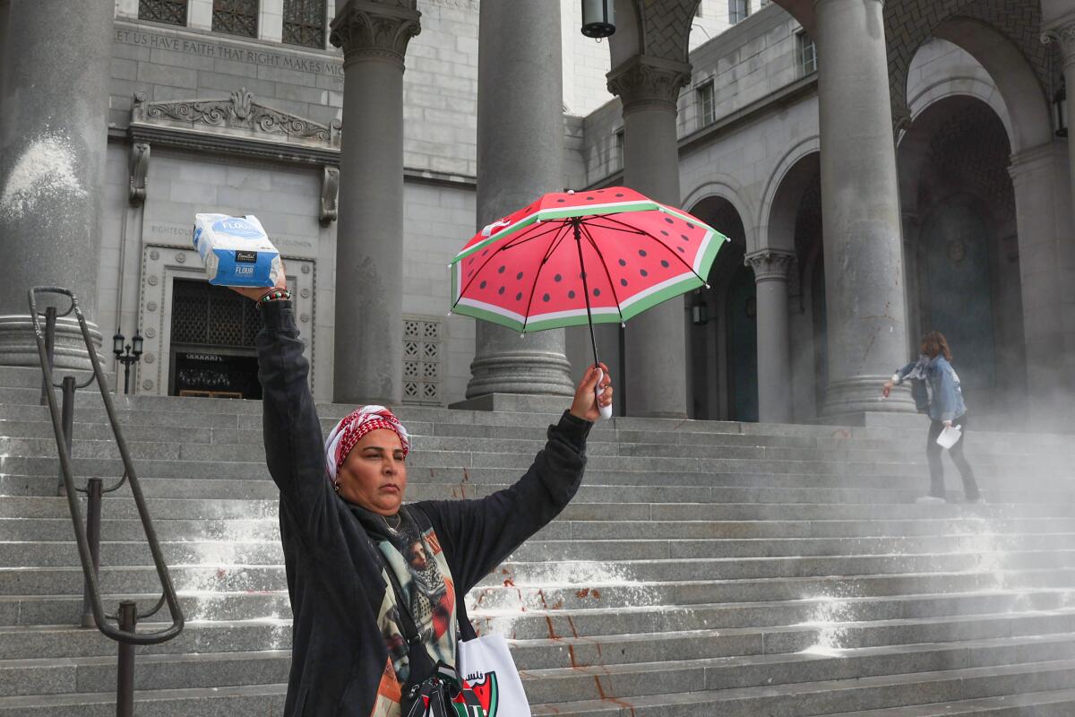 Un manifestant tient un parapluie et un sac de farine, debout près des escaliers éclaboussés de poudre blanche.