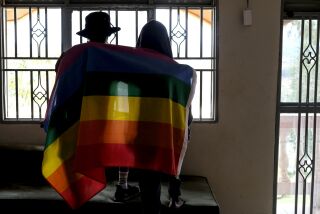 FILE - A gay Ugandan couple cover themselves with a pride flag as they pose for a photograph in Uganda on March 25, 2023. Uganda's president Yoweri Museveni has signed into law tough new anti-gay legislation supported by many in the country but widely condemned by rights activists and others abroad, it was announced Monday, May 29, 2023. (AP Photo, File)
