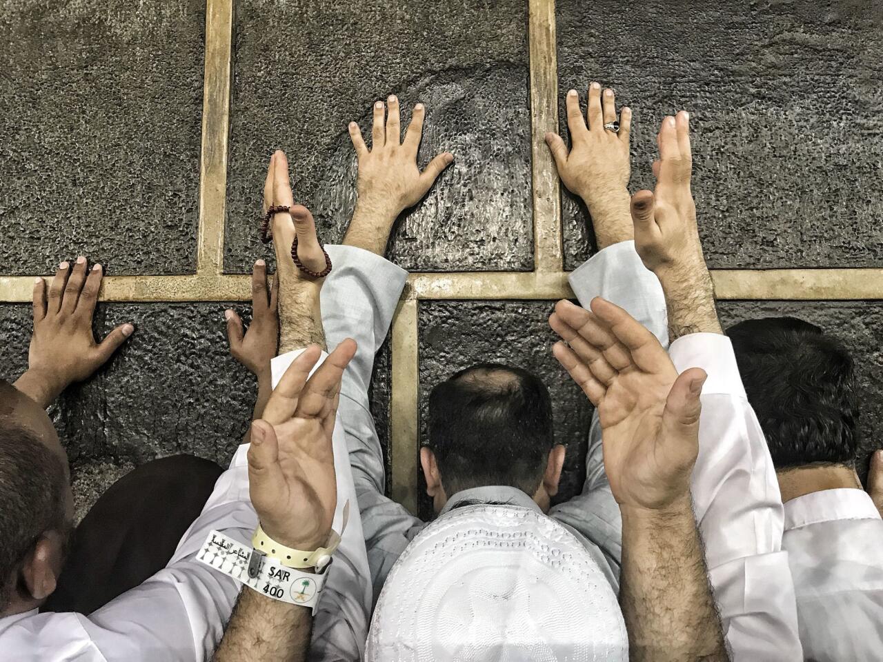 Hajj pilgrims touch the wall of the Kaaba, Islam's holiest site, in the Saudi Arabian city of Mecca on Saturday. About 2 1/2 million Muslims are expected to take part in the pilgrimage to Mecca this year.