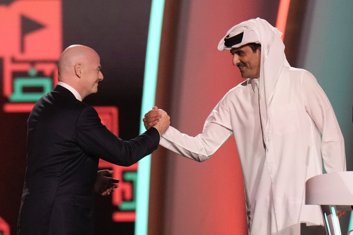 FIFA President Gianni Infantino, left, and Emir of Qatar Sheikh Tamim bin Hamad Al Thani shake hands before the 2022 soccer World Cup draw at the Doha Exhibition and Convention Center in Doha, Qatar, Friday, April 1, 2022. (AP Photo/Hassan Ammar)