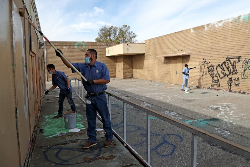 Ocean View School District workers remove graffiti at Park View School on Wednesday in Huntington Beach. 