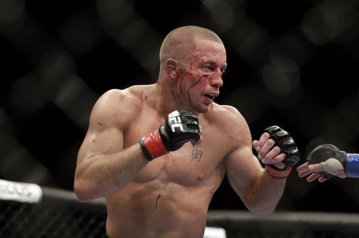 Georges St-Pierre is bloodied by Johny Hendricks during their welterweight bout Saturday at UFC 167 in Las Vegas. St-Pierre won by split-decision.