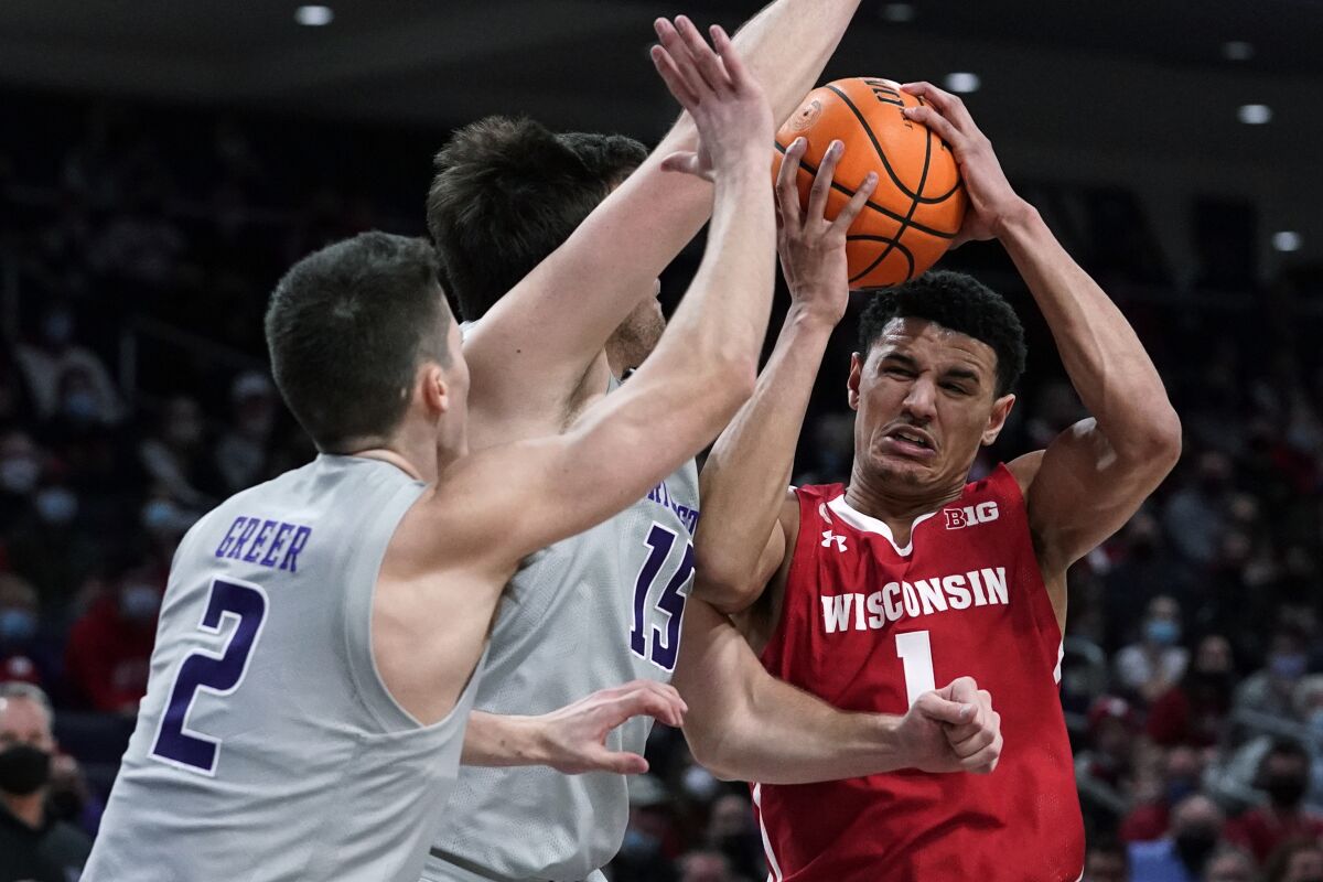 Wisconsin guard Johnny Davis, right, drives to the basket against Northwestern guard Ryan Greer (2) and center Ryan Young during the first half of an NCAA college basketball game in Evanston, Ill., Tuesday, Jan. 18, 2022. (AP Photo/Nam Y. Huh)