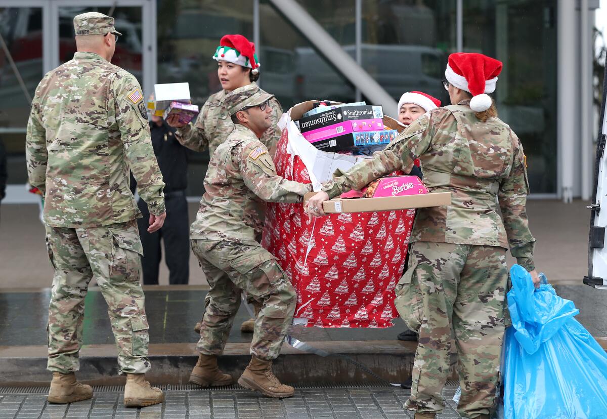 Members of local branches of the military load a truck with hundreds of toys donated by city of Newport Beach.