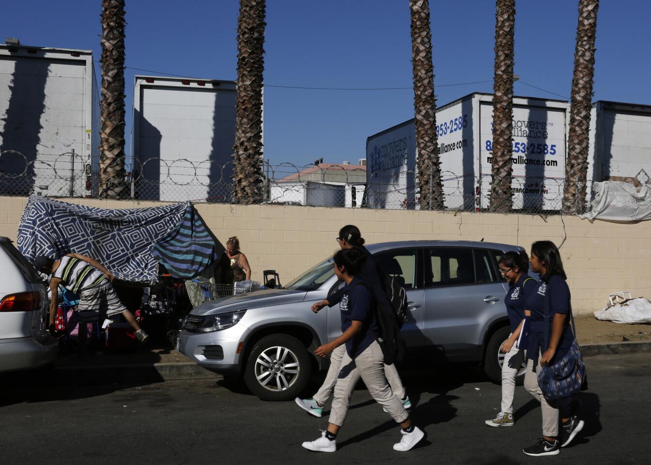 Students pass by homeless people who have set up camp across from the charter school. Administrators have been frustrated in their attempts to have them moved from Cosmopolitan Street in Koreatown.