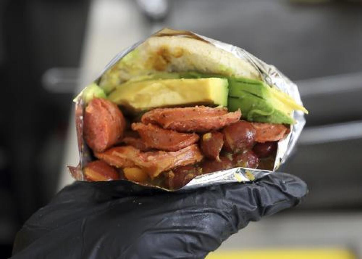 En esta imagen del 11 de junio de 2019, un empleado muestra una arepa venezolana hecha con ingredientes colombianos en el restaurante de comida rápida "Arepas Cafe" en Bogotá, Colombia. (AP Foto/Fernando Vergara)