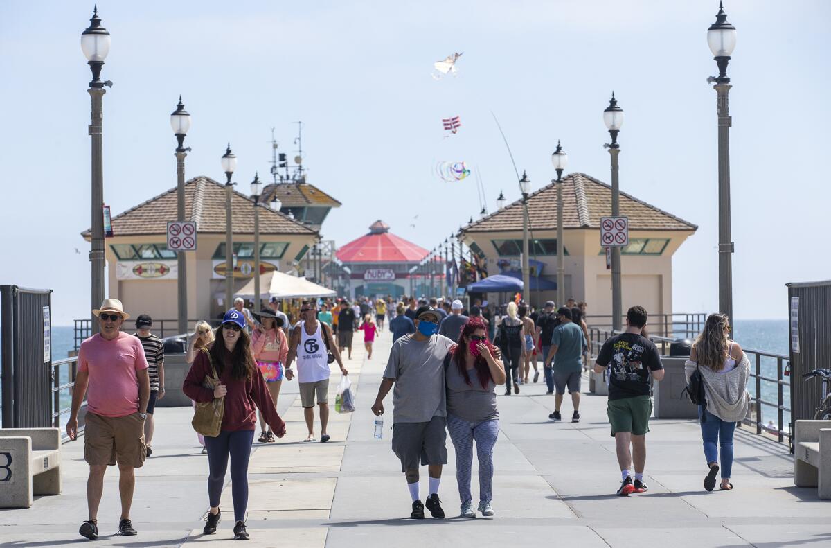 People walk along the Huntington Beach Pier after it opened on Tuesday for the first time since March.