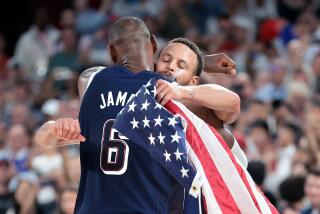 LeBron James embraces Stephen Curry who is carrying an American flag after they beat France 