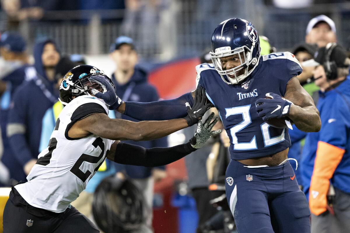 Tennessee Titans running back Derrick Henry stiff arms Jacksonville Jaguars safety Jarrod Wilson.