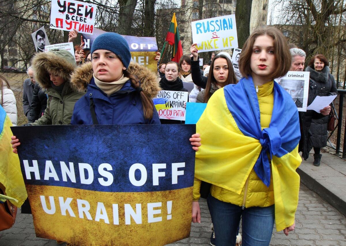 Demonstrators wear the Ukrainian flag and hold posters reading "Hands off Ukraine" during a protest of Russia's intervention in Ukraine at the Russian Embassy in Vilnius, Lithuania, on March 3, 2014.