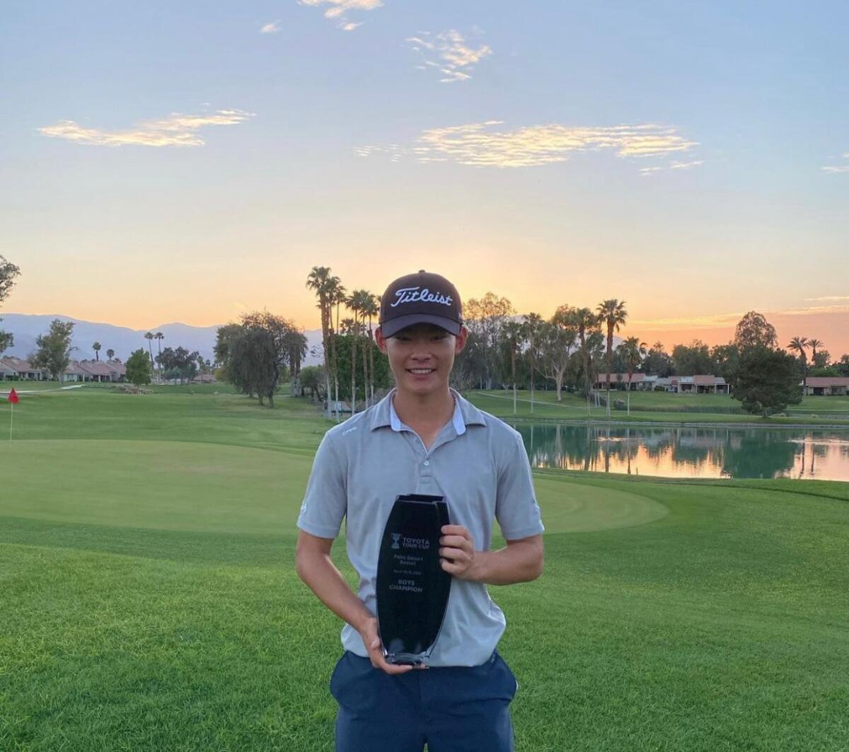 Joshua Koo of Cerritos shows his prize while standing on a golf course.