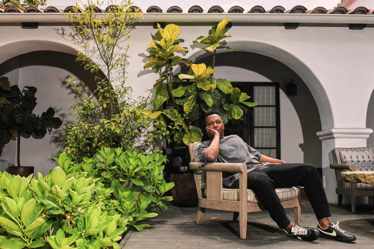 Leslie Odom Jr. sits back in a patio chair.